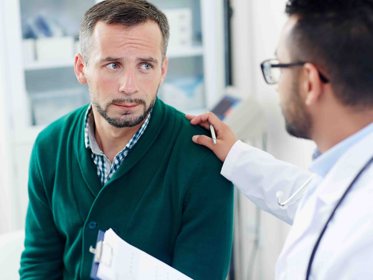 A concerned man consulting with a doctor about the best age to get a hair transplant.