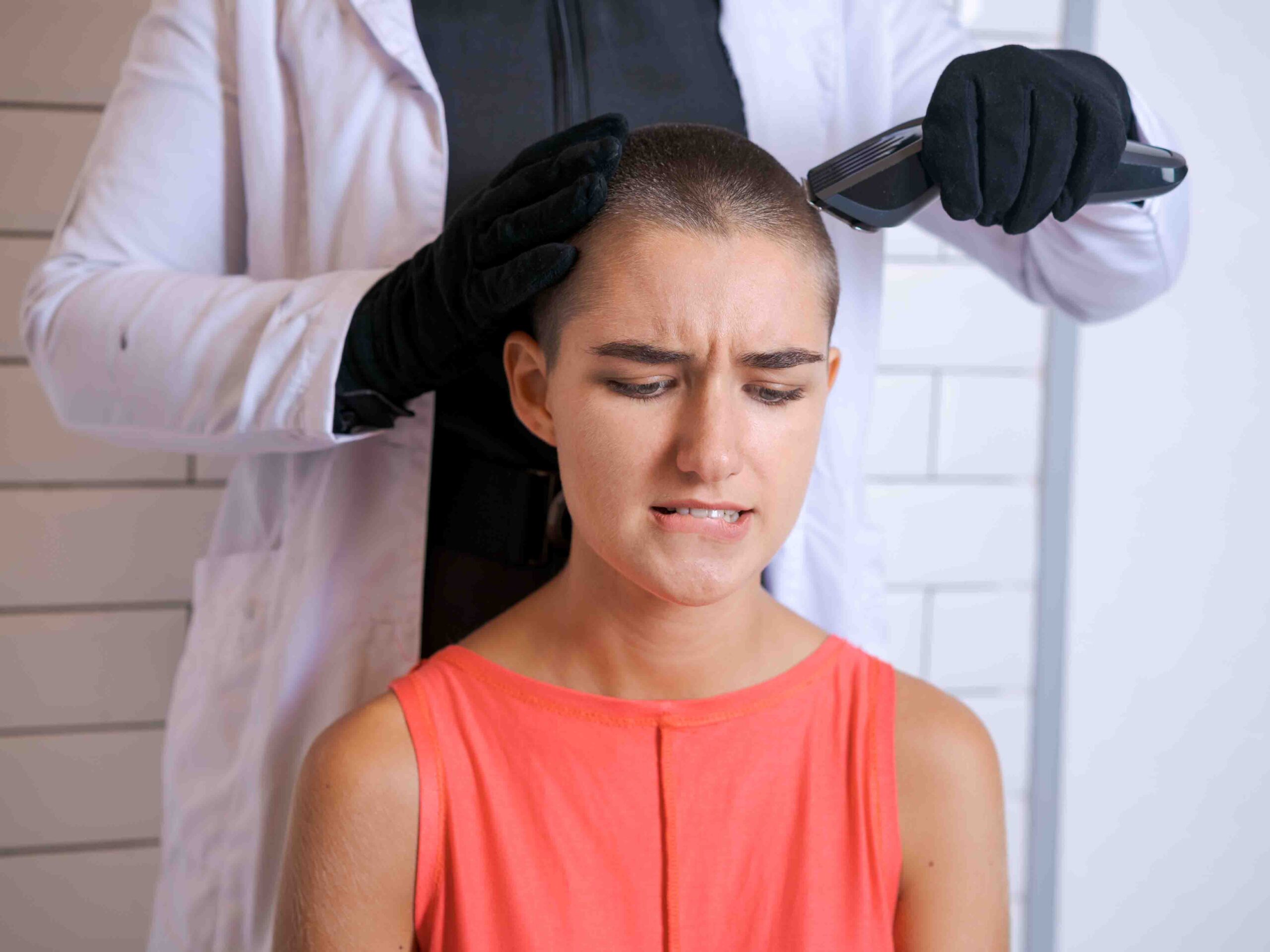 Examining for a hair transplant for women with her head being shaved by a medical professional in a clinic setting.