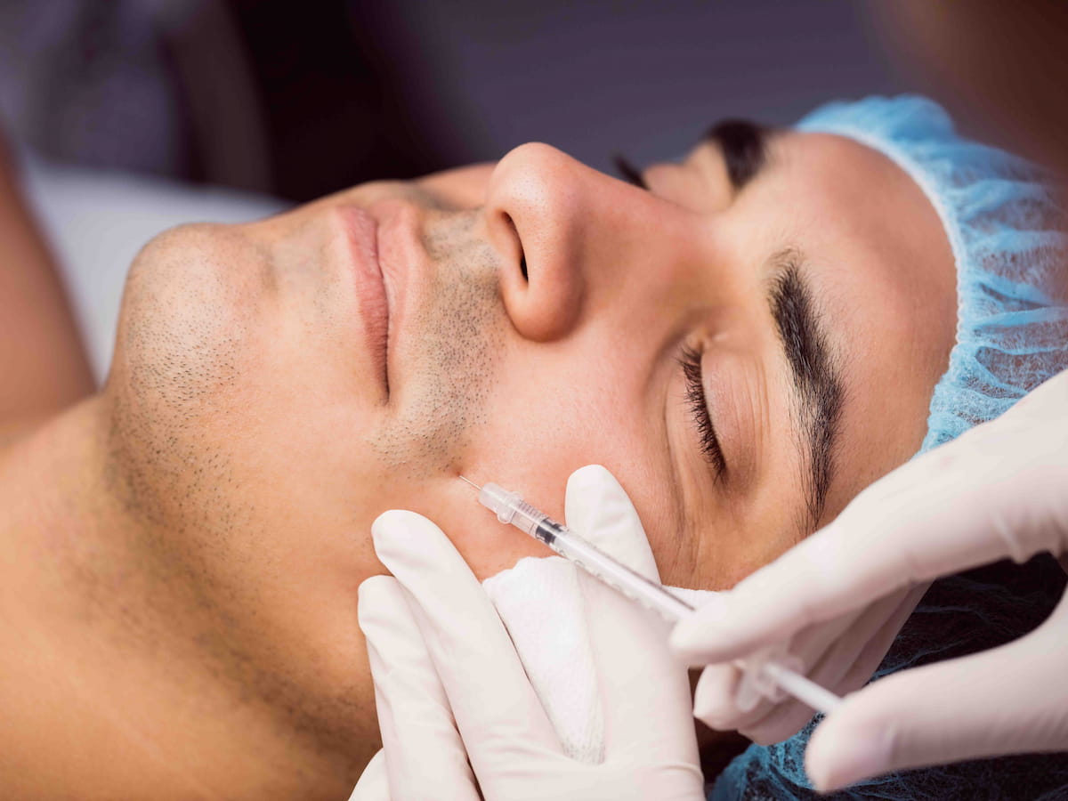 A man undergoing mustache hair transplant at a professional clinic in Dubai, with a specialist performing an injection procedure.